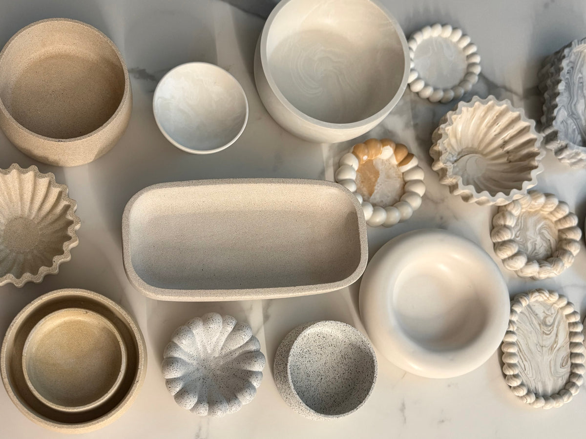 Flat lay of handcrafted Omora handrafted pieces in natural stone-inspired finishes.