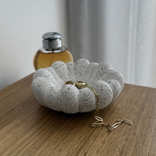 Cove decorative bowl in textured stone-inspired finish styled on timber table with jewellery and a perfume bottle.
