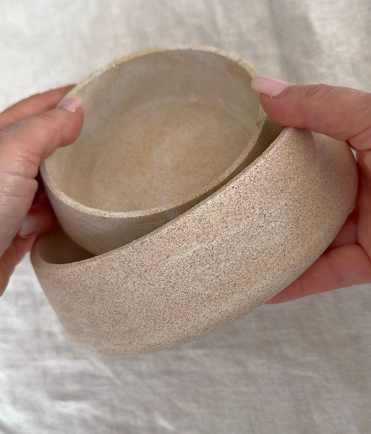 Close up of hands holding  a set of handcrafted Omora bowls, celebrating thoughtful design and craftsmanship.