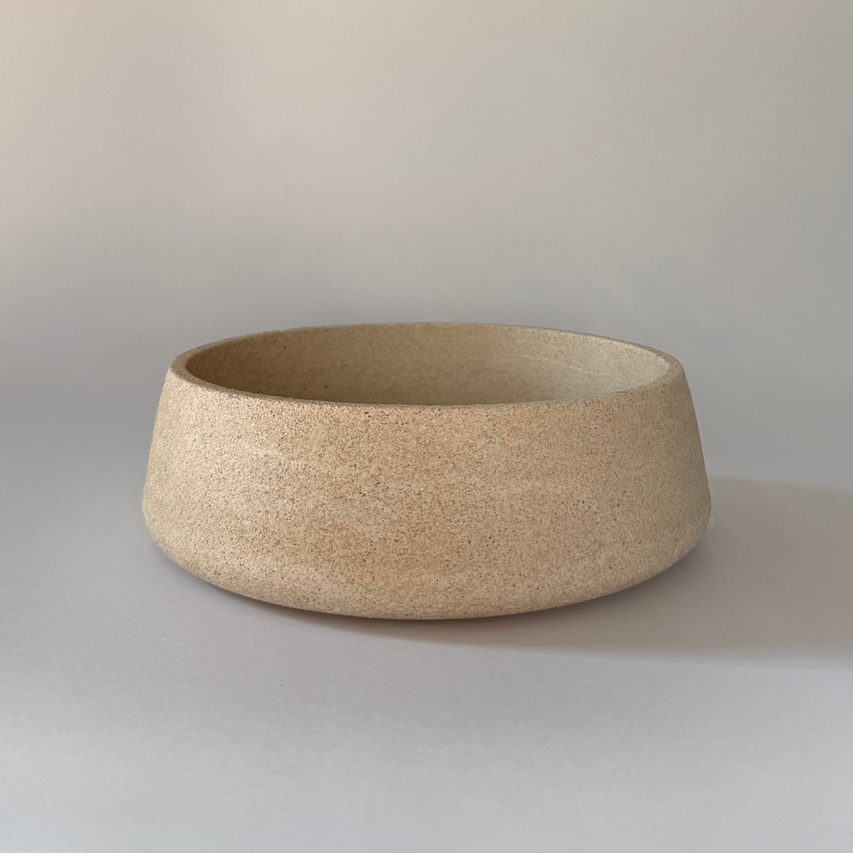 Handcrafted Dune Bowl showcasing it's softly curved form and textured stone-inspired finish.