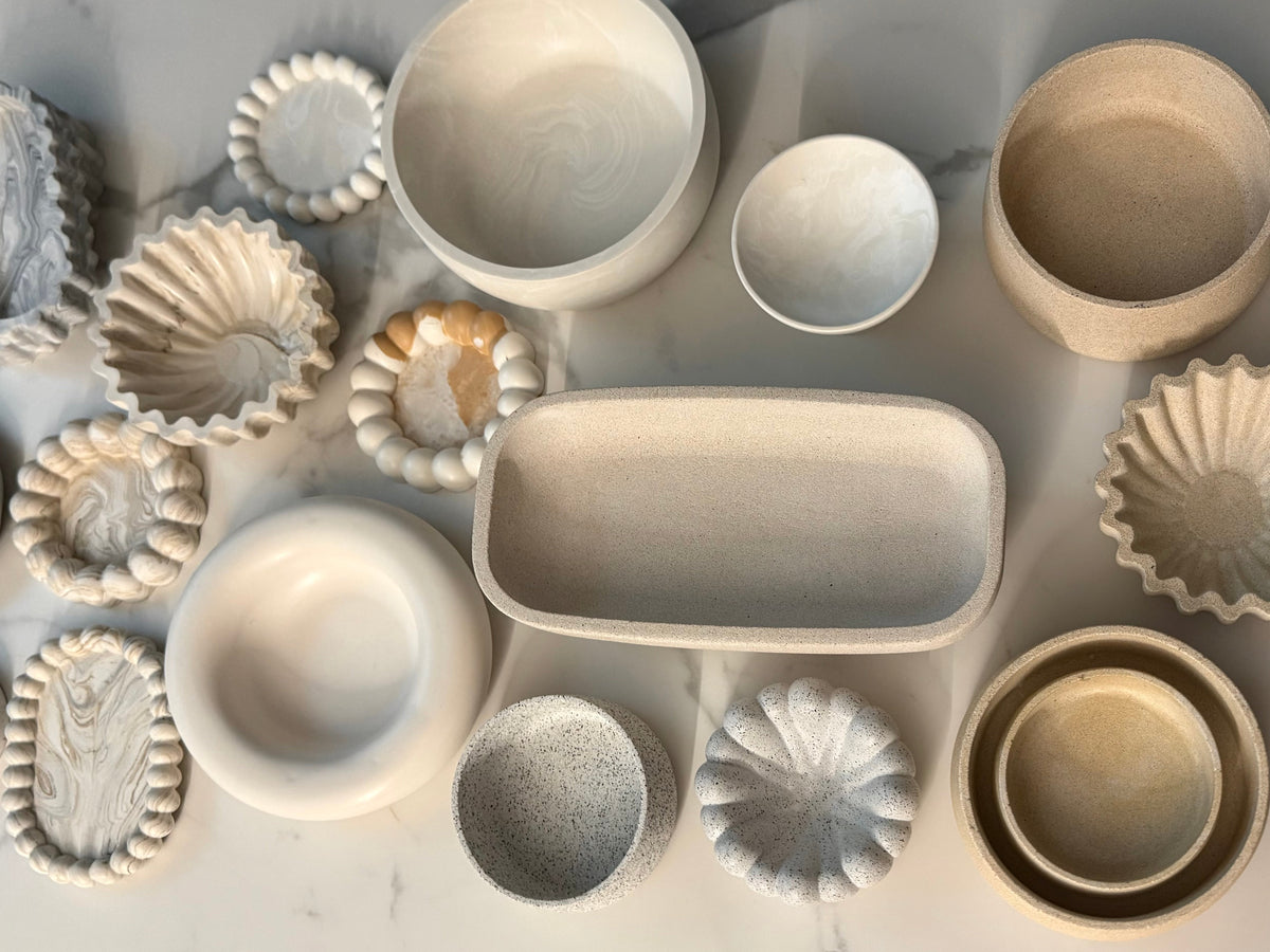 Flat lay of handcrafted Omora handrafted pieces in natural stone-inspired finishes.