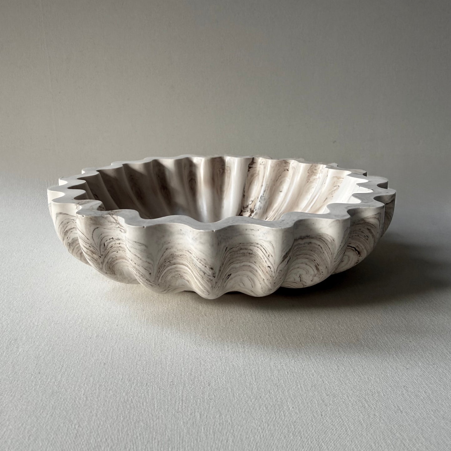 Side profile of handcrafted Ripple Bowl, showcasing it's sculptural rippled edges and smooth marble-inspired finish.