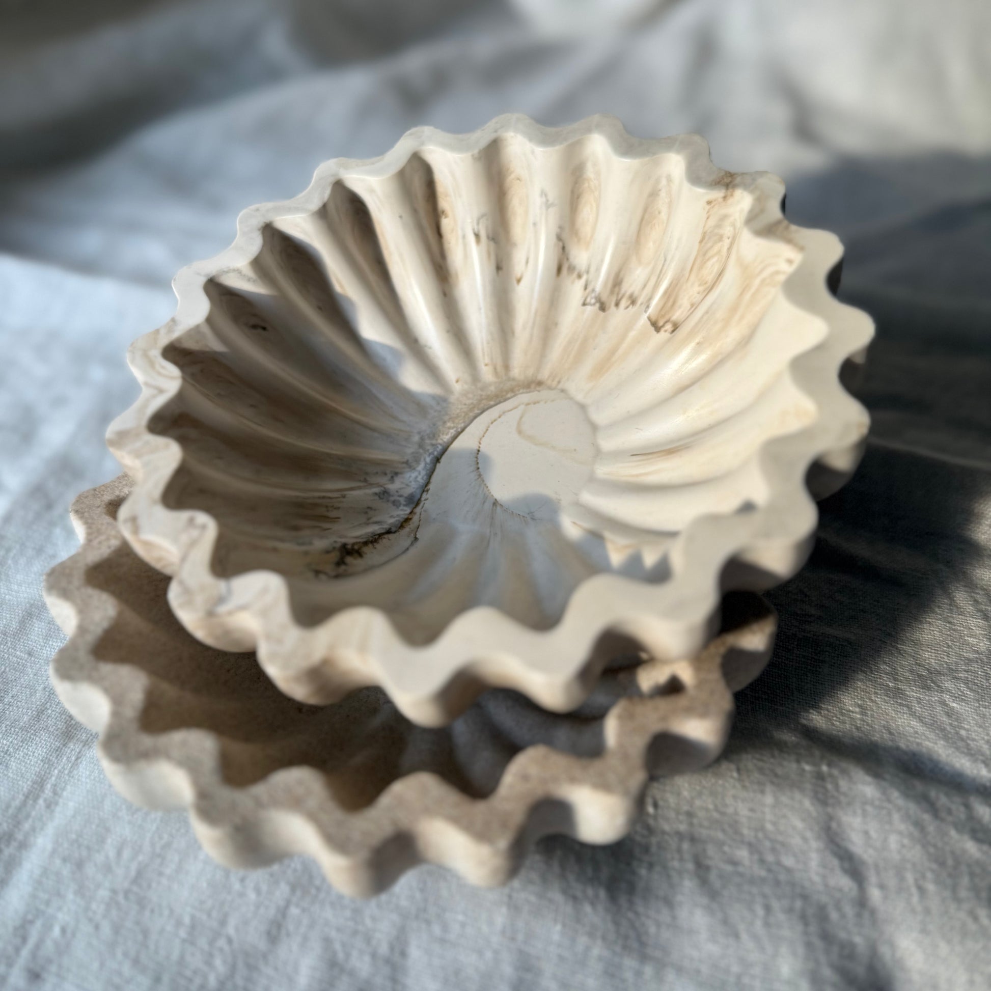 Two handcrafted Ripple Bowls stacked together, showcasing their scuptural rippled edges and stone-inspired finish