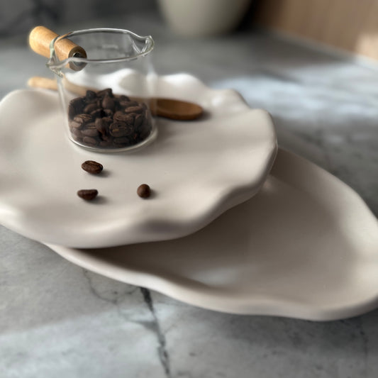 Two stacked handcrafted Shore Trays in smooth natural stone-inspired finish styled with glass coffee server and coffee beans.