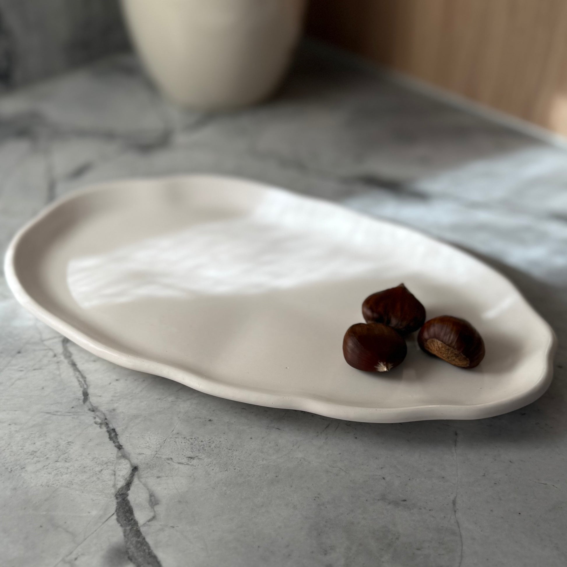 Long handcrafted Shore Tray in smooth natural stone-inspired finish styled with chestnuts.