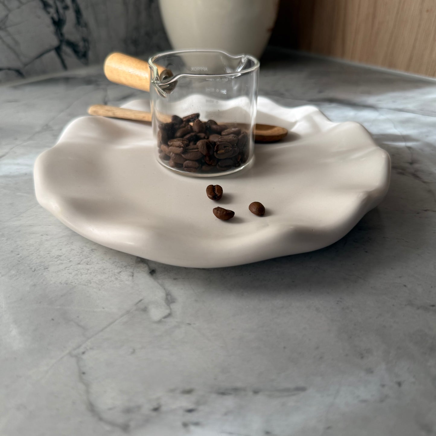 Round handcrafted Shore Tray in smooth natural stone-inspired finish styled with glass coffee server and coffee beans.