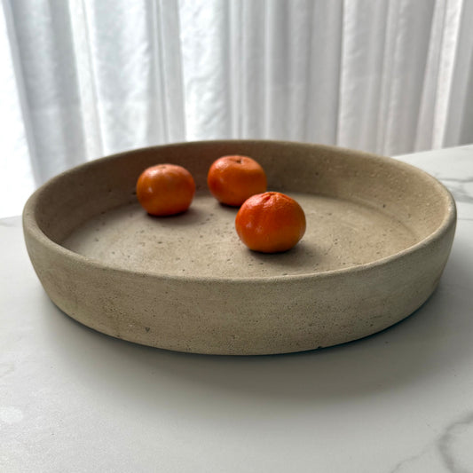 Handcrafted Terra Bowl with an aged travertine finish and natural stone texture, styled with fresh mandarins on a soft linen backdrop.