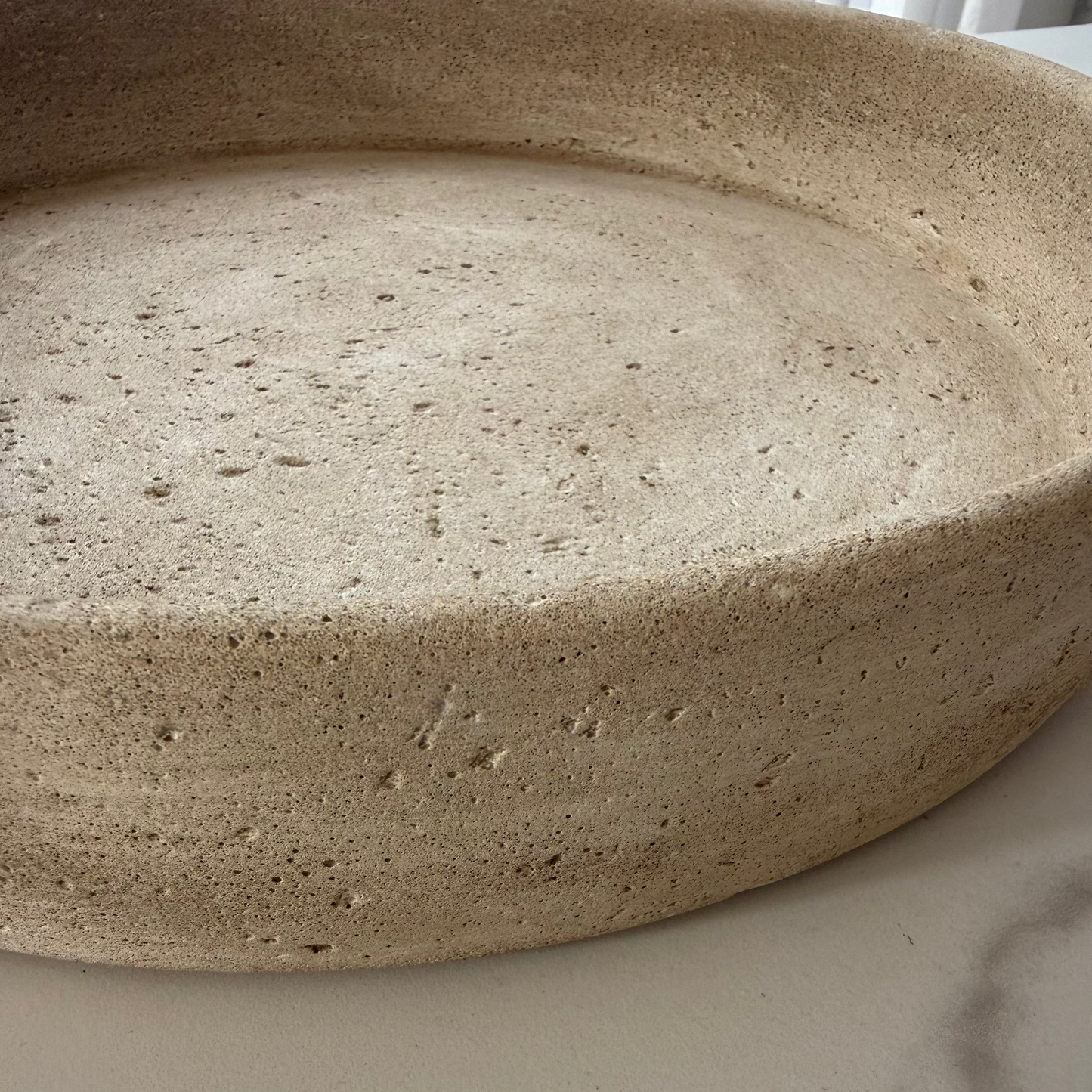A close-up of the handcrafted Terra Bowl, showing its natural texture, color and surface, resting on a white marble countertop.