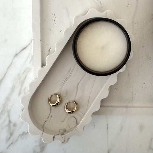 View from above of handcrafted Tide Tray highlighting the collection's sculptural silhouette styled with a candle and earrings.