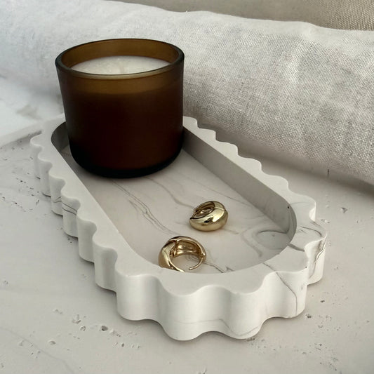 Handcrafted Tide Tray highlighting the collection's sculptural silhouette and styled with a candle and earrings